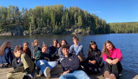 Genoese students sitting on a platform by a lake.