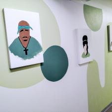 Käytävä, jonka seinällä on kolme ikonista muotokuvaa: Tupac Shakur, Amy Winehouse ja kolmas henkilö, taustana vaaleanvihreä graafinen seinäkuvio.
