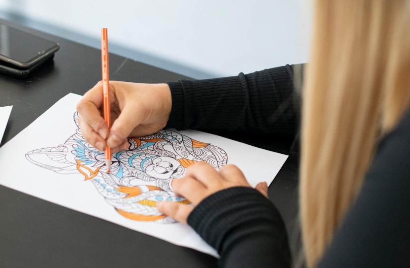 Opiskelija värittää mindfulness-värityskuvaa.